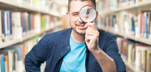 Young man wearing a blue outfit. Using a magnifying glass. Smili